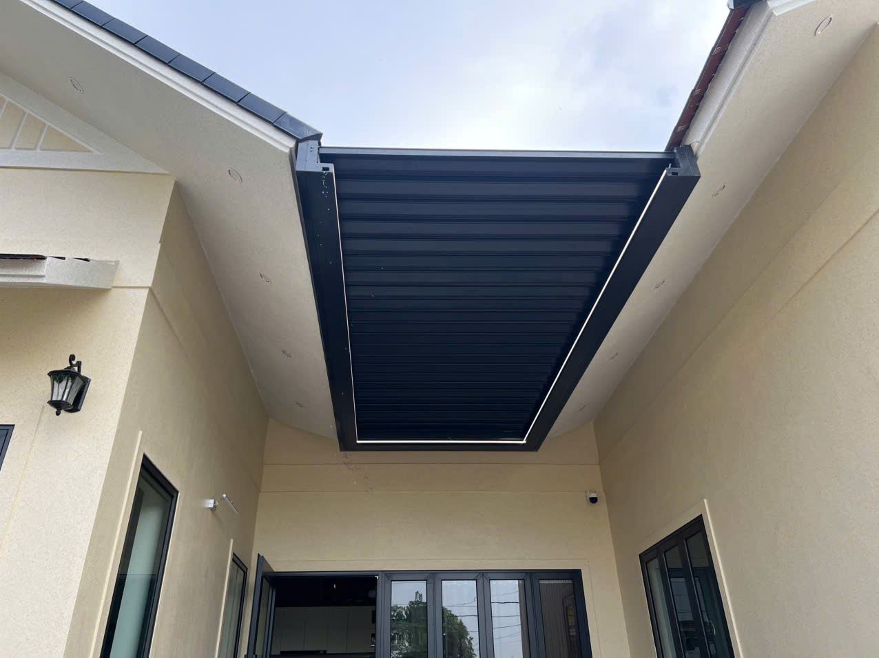 Mái nhôm xếp tự động che sân trong giữa hai khối nhà